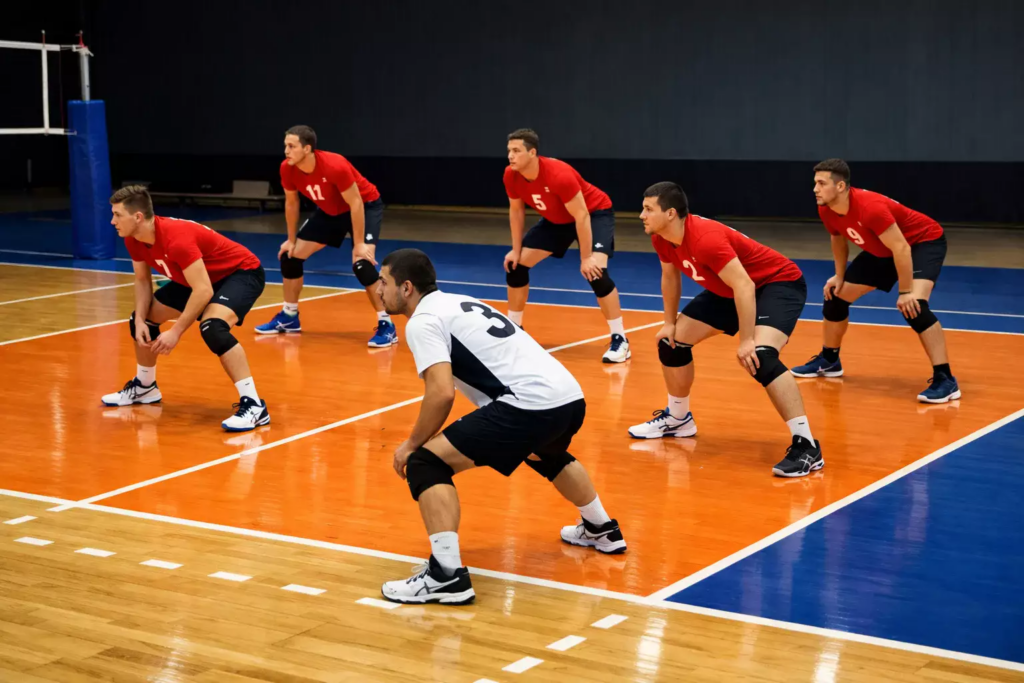 Équipe de volley-ball en position de réception sur terrain indoor